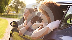 Two Female Friends Or Same Sex Couple In Car On Road Trip Vacation Together Looking Out Of Window