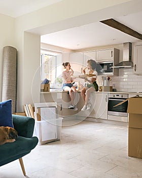 Two Female Friends Or Same Sex Couple Celebrating With Pizza And Wine On Moving Day In New Home