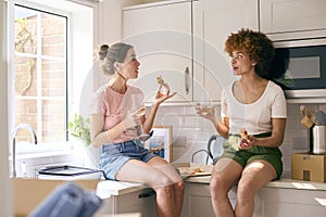 Two Female Friends Or Same Sex Couple Celebrating With Pizza And Wine On Moving Day In New Home