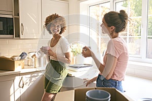 Two Female Friends Or Same Sex Couple Taking A Coffee Break From Unpacking On Moving Day In New Home