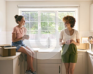 Two Female Friends Or Same Sex Couple Taking A Coffee Break From Unpacking On Moving Day In New Home