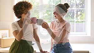 Two Female Friends Or Same Sex Couple Taking A Coffee Break From Unpacking On Moving Day In New Home