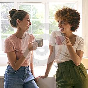 Two Female Friends Or Same Sex Couple Taking A Coffee Break From Unpacking On Moving Day In New Home