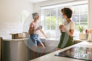 Two Female Friends Or Same Sex Couple Taking A Coffee Break From Unpacking On Moving Day In New Home