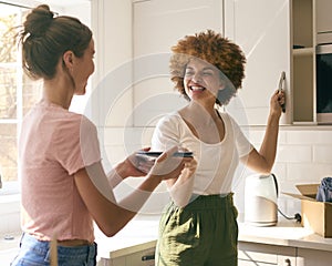 Two Female Friends Or Same Sex Couple Unpacking On Moving Day In New Home