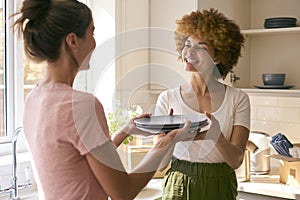 Two Female Friends Or Same Sex Couple Unpacking On Moving Day In New Home