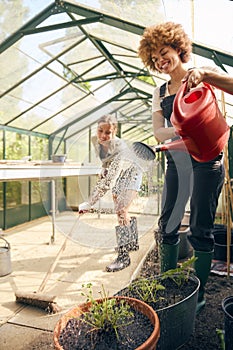 Two Female Friends Or Same Sex Couple Working In Greenhouse At Home Together