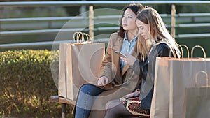 Two female friends shopping online with smartphone