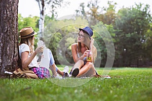 Two female friends sitting on the grass, talking