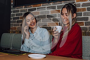 Two female friends talking and drinking coffee in cafe