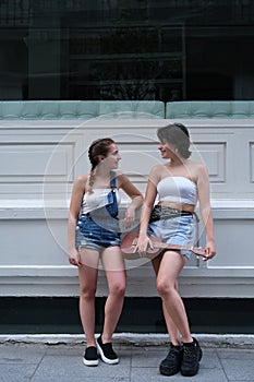 Two female friends talking and holding a ukelele on a city street.