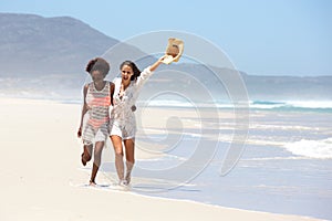 Two female friends walking barefoot on the beach