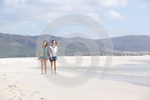 Two female friends walking on empty beach together
