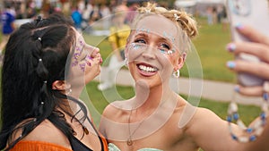 Two Female Friends Wearing Glitter Posing For Selfie At Summer Music Festival 