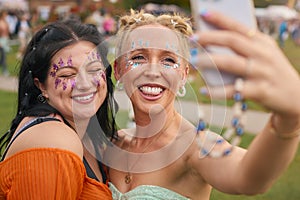 Two Female Friends Wearing Glitter Posing For Selfie At Summer Music Festival 