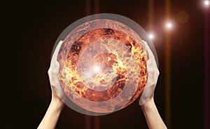Two female hands hold a red-hot globe on a black background.Elements of this image are provided by NASA. The concept of global