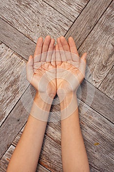 Two female hands showing open palms on wooden background.