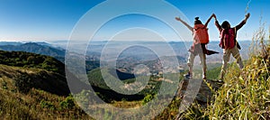 Two female hikers climbing up mountain cliff