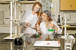 Two female laboratory technicians researching medical samples and reagents for coronavirus vaccination