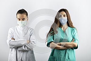 Two female nurses in medical masks looking at camera