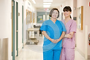 Two Female Nurses Standing In A Hospital Corridor