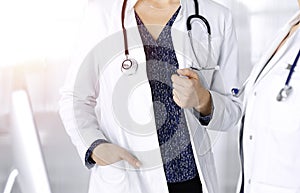 Two female physicians are discussing medical therapy, while standing at the table in a sunny clinic office. Doctors use