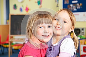 Two Female Pre School Pupils Hugging One Another