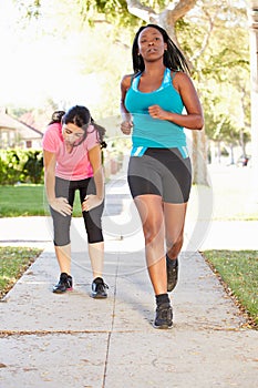 Two Female Runners Exercising On Suburban Street