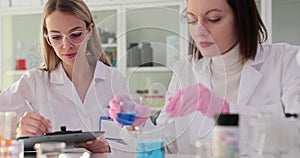 Two female scientists conduct detailed study of reagent in laboratory office.