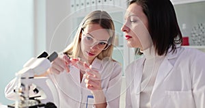Two female scientists examine a test tube with red liquid