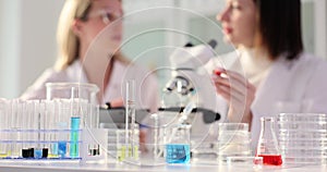 Two female scientists working in a laboratory and a scientist is looking through microscope and dripping liquid