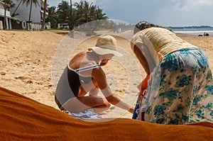 Two female seller and buyer are haggling on a Sri Lankan beach, for merchandise clothing, local products and seller