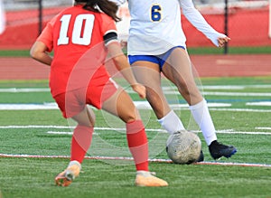 Two female soccer players fighting for possession of the soccer ball