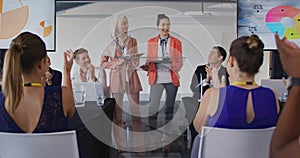 Two female speakers and applauding audience at a business conference