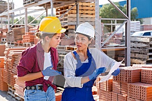 Two female storekeepers are discussing an estimate at the warehouse