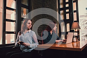 Two female students or lesbians having fun during coffee break at cafe, second half distract from work.