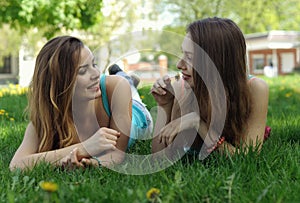 Two female students lie on the grass