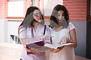 Two female students preparing for exams together outdoors on the campus