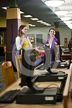 Two female students standing by library computers