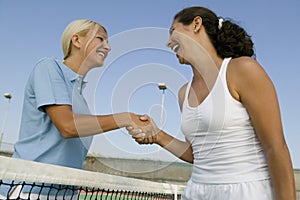 Two female Tennis Players shaking hand over tennis court net low angle view