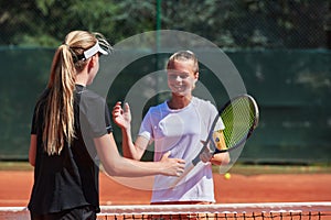 Two female tennis players shaking hands with smiles on a sunny day, exuding sportsmanship and friendship after a