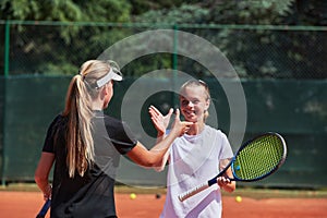 Two female tennis players shaking hands with smiles on a sunny day, exuding sportsmanship and friendship after a