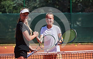 Two female tennis players shaking hands with smiles on a sunny day, exuding sportsmanship and friendship after a