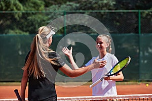 Two female tennis players shaking hands with smiles on a sunny day, exuding sportsmanship and friendship after a