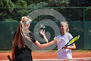 Two female tennis players shaking hands with smiles on a sunny day, exuding sportsmanship and friendship after a