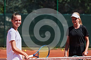 Two female tennis players shaking hands with smiles on a sunny day, exuding sportsmanship and friendship after a