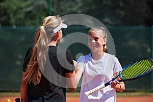 Two female tennis players shaking hands with smiles on a sunny day, exuding sportsmanship and friendship after a