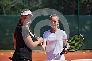 Two female tennis players shaking hands with smiles on a sunny day, exuding sportsmanship and friendship after a