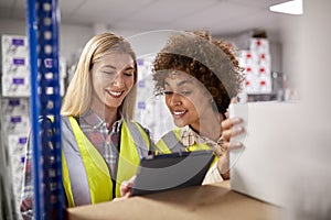 Two Female Workers In Logistics Distribution Warehouse Using Digital Tablet