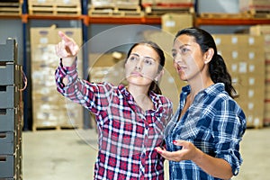 Two females discussing working process at warehouse